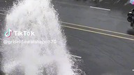 a queue of cars under a broken hydrant to wash the car for free
