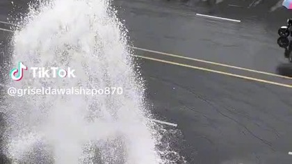 a queue of cars under a broken hydrant to wash the car for free