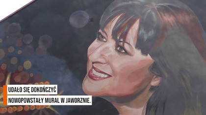 Basia Trzetrzelewska na muralu.  Uśmiecha się do przechodniów