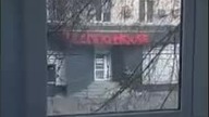 Żołnierz rosyjski strzela do drzwi i pr&oacute;buje wejść do sklepu.